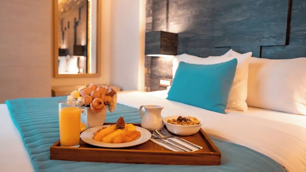 Habitación Ejecutiva con cama matrimonial en el Hotel Punto MX. Se ve una charola con el desayuno en la cama.